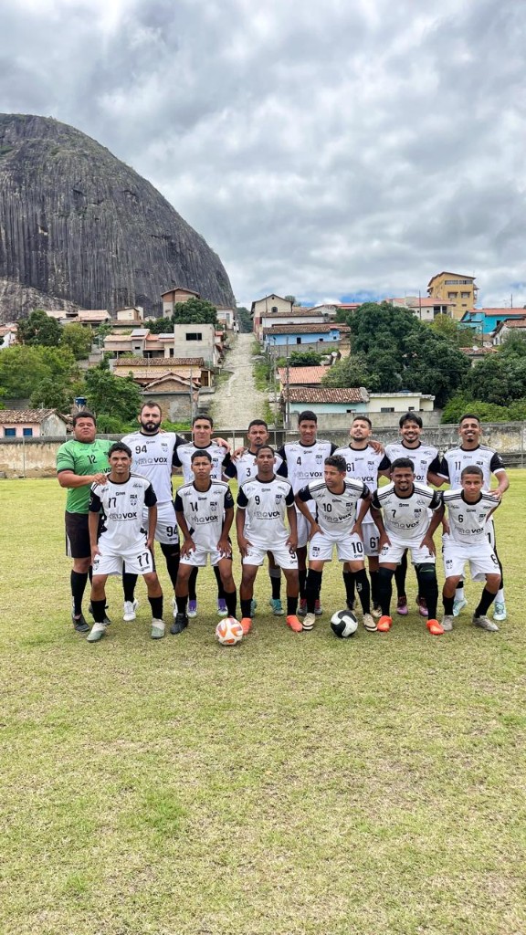 Equipa em campo com montanha e vila ao fundo